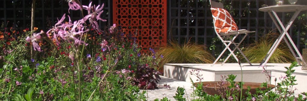 wildflowers growing in a small garden with white paving and bright seating area